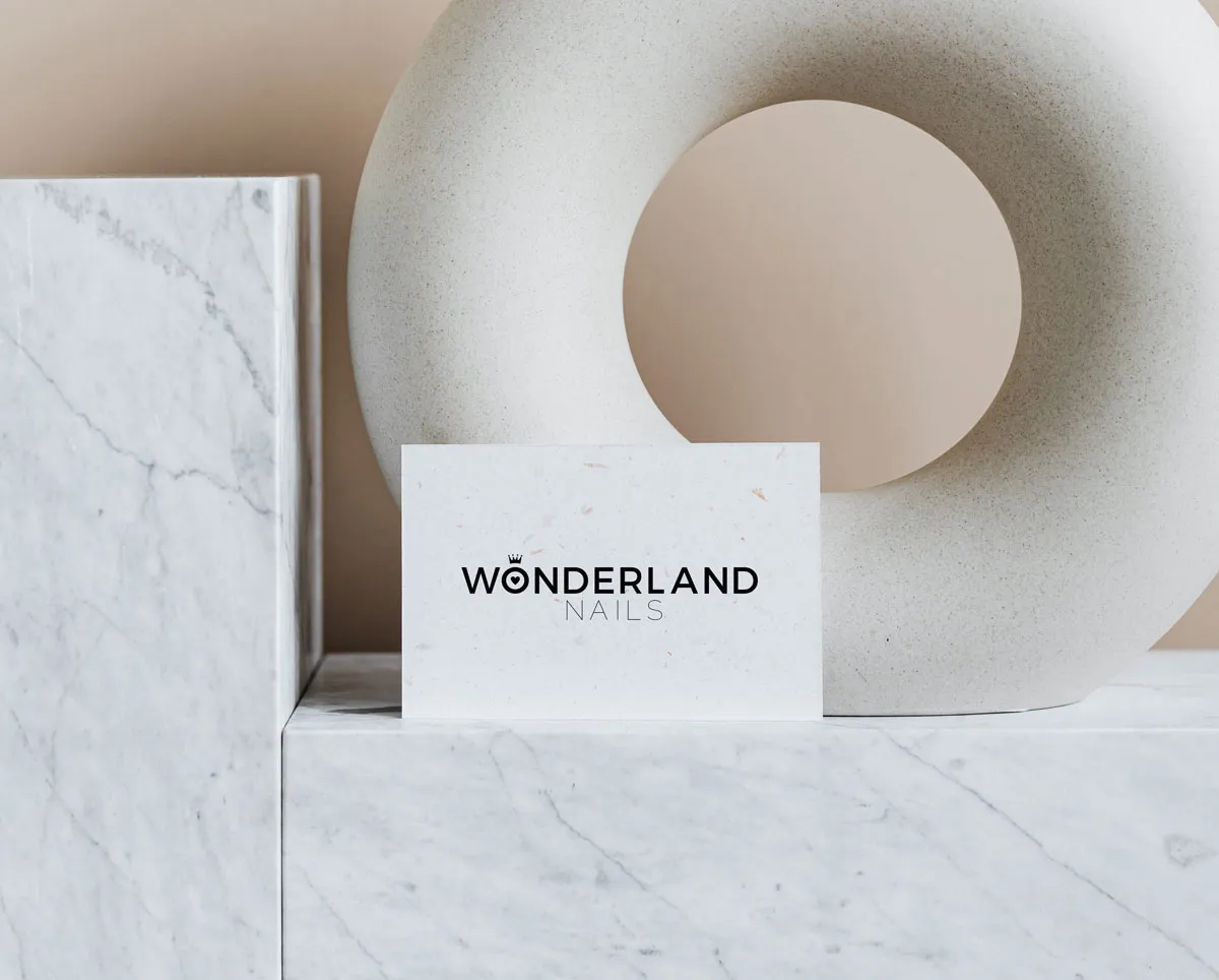 Wonderland Nails logo card on marble and white ceramic